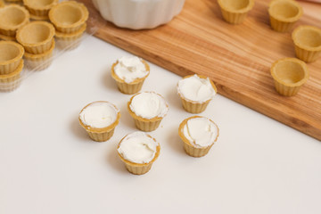 Tartlets with custard or cottage cheese. Empty tartlets or pie on a white table. Food lay flat. The view from the top. The concept of preparing food for the holiday table.