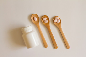 Assorted pharmaceutical medicine. Dosage. Tablets and capsules on a wooden spoon on a white background. Concept of medicine. Alternative homeopathy. Flatley.   copyright of the text.