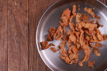 Fried chicken skin on wood table.