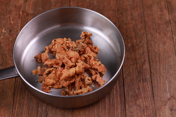 Fried chicken skin on wood table.