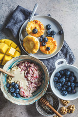 Breakfast background. Oatmeal, cottage cheese pancakes with berries and fruits on dark background.