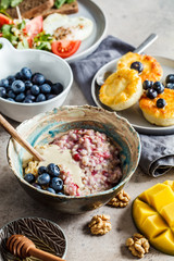 Breakfast flat lay. Oatmeal, cottage cheese pancakes with berries and fried egg with salad on dark background.