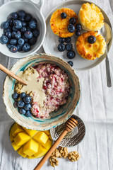 Breakfast background. Oatmeal, cottage cheese pancakes with berries and fruits on dark background.