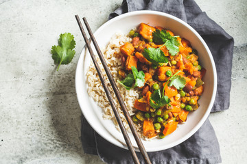 Vegan curry with rice in white bowl, top view. Curry with sweet potato, peas and beans in a plate with rice.