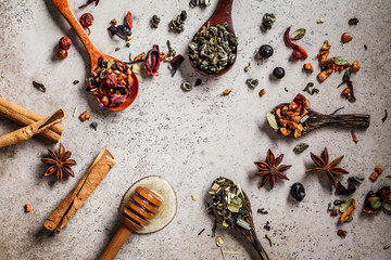 Different herbal tea with honey and spices on a brown background.