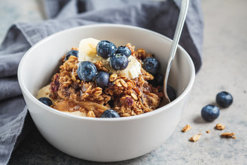 Homemade granola bowl with blueberries, banana and honey.