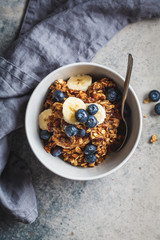 Homemade granola bowl with blueberries, banana and honey, top view.