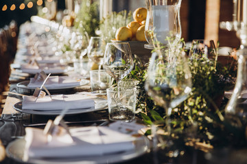 in the back yard of the old villa there is a long festive table, which is decorated with lemons and herbs, on the table are plates, glasses and candles. Wedding in Italy. Tuscany