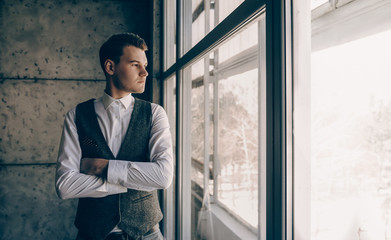 The photo of a beautiful man who is looking through the window and thinking about something big and innovative