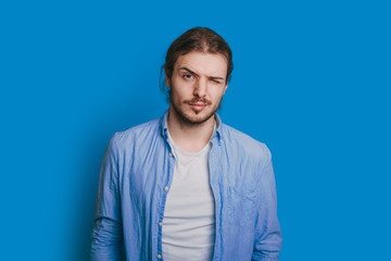 The image of a man who is dressed in a nice shirt having a confident look and blinking on a sky-blue background