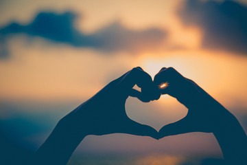 Hands make in heart form love with silhouette at sun set