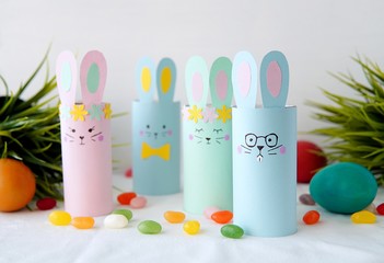 Colorful Easter decorations bunnies made from toilet paper roll,  easy paper crafts for kids, painted eggs and candies.                  
