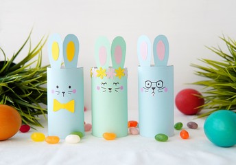 Colorful Easter decorations bunnies made from toilet paper roll,  easy paper crafts for kids, painted eggs and candies.                  
