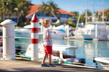 Child watching yacht and boat in harbor. Yachting.