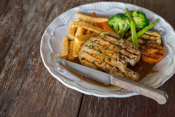 Black pepper pork chop in white plate on wooden table