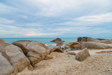 Fototapeta na wymiar Sea and rock stones on the beach with sand and blue sky