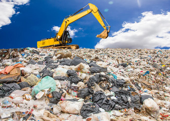 garbage dump pile in trash dump or landfill,backhoe is dumping the gabage from municipal,garbage...