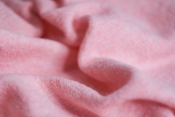 soft knitted fabric made of cashmere with large folds, a detail of clothes. pink fabric texture