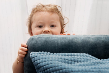 Toddler face peeking behind couch