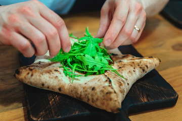 the cook starts the pizza with arugula. chef's hands close up