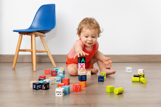Cute baby piling up blocks in playroom