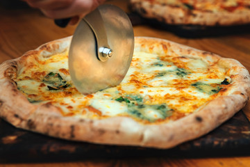 Cook cuts pizza with roller knife. Chef cut roller knife freshly baked pizza. Cutting delicious...