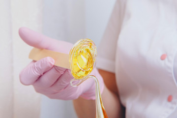 Wax for depilation close-up. girl pulls out cosmetic product from jar. Hand with wooden stick for...