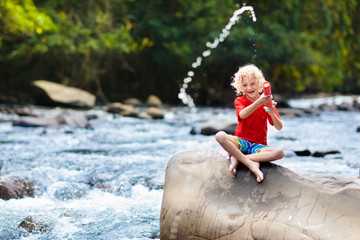 Child hiking in mountains. Kids at river shore.