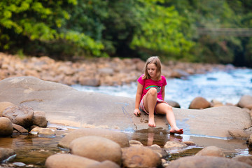Child hiking in mountains. Kids at river shore.