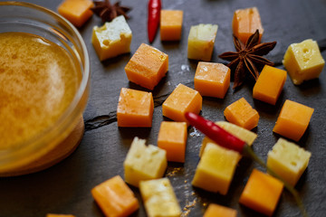pieces of different cheese with honey on a stone plate