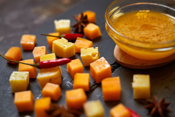 pieces of different cheese with honey on a stone plate