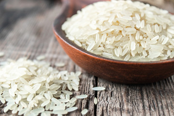 A bowl of white rice against the background of old boards near sprinkled rice. Jasmine rice for cooking.