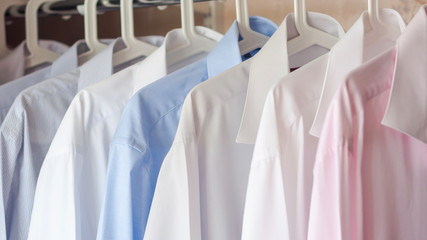 multi-colored ironed men's shirts hang on a hanger, selective focus