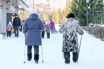 Nordic walking in Russia. Grandmothers walk in the winter with sticks. Sports for the elderly
