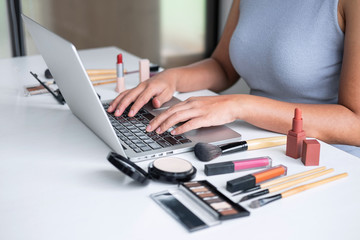 Business online on social media, Beautiful woman is watching online blogger tutorial on laptop, showing present tutorial beauty cosmetic using product makeup