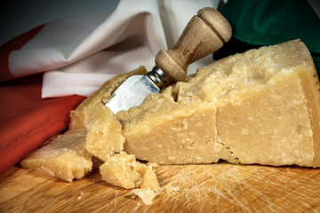 Close-up of Parmesan cheese on a wooden cutting board with knife and Italian flag