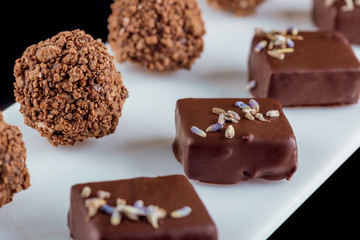Copyrighted original handmade chocolate candies on a white board. Black background. Close-up.