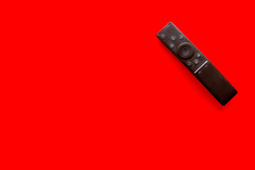 Television air recording concept. TV remote on red background top-down copy space