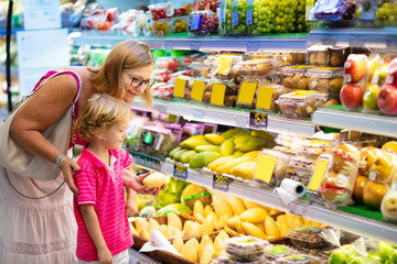 Mother and child buying fruit in supermarket.