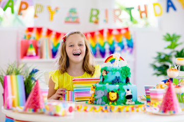 Child birthday party. Kids blow candle on cake.