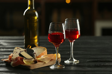Glasses and bottle of delicious wine with snacks on table in bar