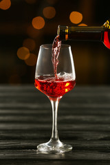 Pouring of delicious wine from bottle into glass on table in bar