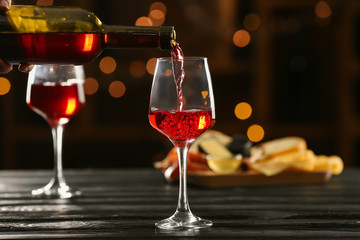 Pouring of delicious wine from bottle into glass on table in bar