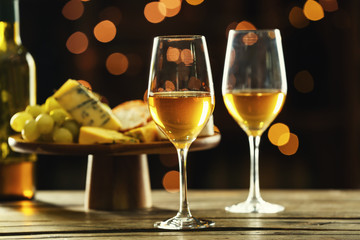 Glasses of delicious wine with cheese on table in bar