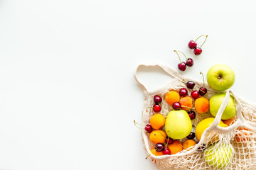 Textile eco bag with fruits on white background top-down copy space