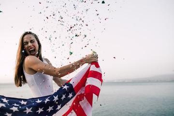 beautiful woman holding American flag with confetti blowing