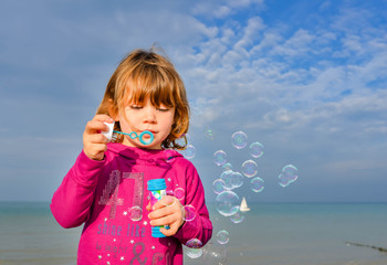 beautiful little girl blowing soap bubbles