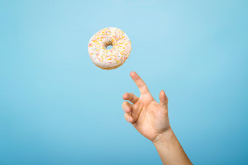 Hand catch a donut with icing. Blue cardboard background. Concept of baking, handmade. Flat lay,...