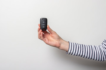 female hand holds a car key on a white background