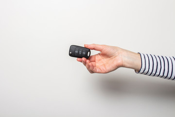 female hand holds a car key on a white background